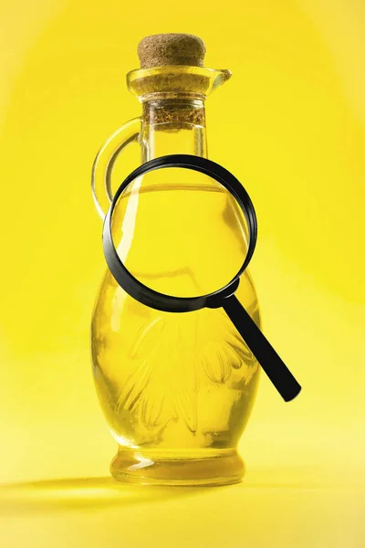A magnifying glass on the background of an oil bottle — Stock Photo, Image