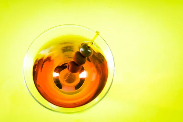 Martini glass with green olives on a yellow background — Stock Photo, Image