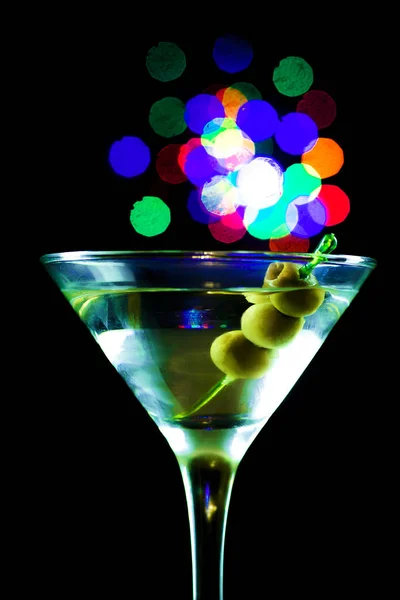 Sklenička na Martini se zelenými olivami na černém pozadí — Stock fotografie
