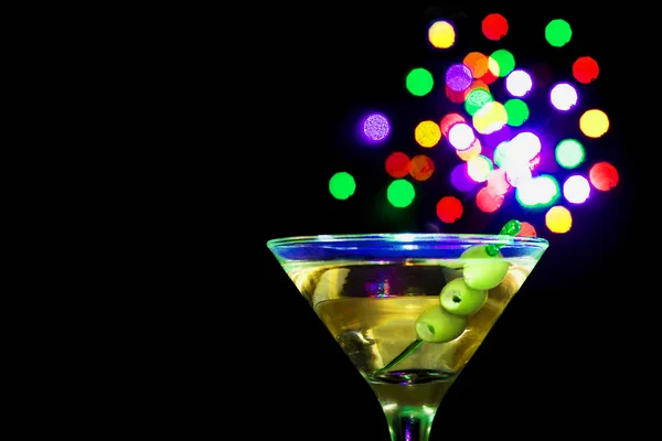 Een Martini glas met groene olijven op een zwarte achtergrond — Stockfoto