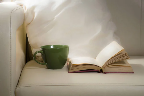 Зеленая кружка и книга, на фоне подушек на кровати — стоковое фото