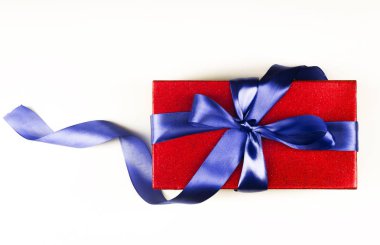 Beyaz arka plan üzerinde mavi fiyonklu kırmızı bir hediye kutusu