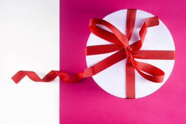 Beyaz-mor arka plan üzerinde kırmızı fiyonklu beyaz kutu