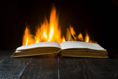 Alevlerin arka planı üzerine açık kitap