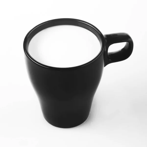 Tasse noire avec du lait sur fond blanc — Photo