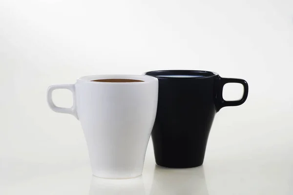 Caneca branca com café e caneca preta com leite em um backgro branco — Fotografia de Stock