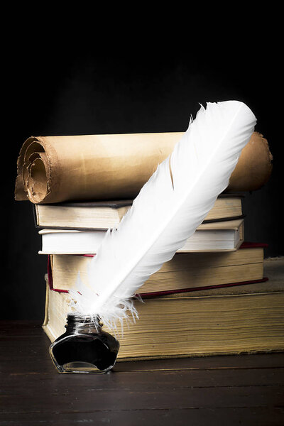 Scrolls of parchment with a pen on a background of a stack of bo