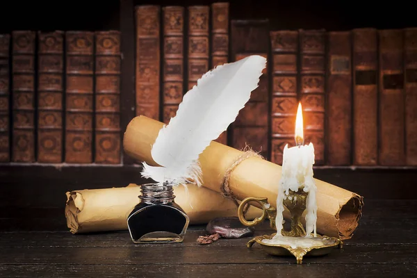 Inkwell with pen, scroll of parchment, and candle against the ba