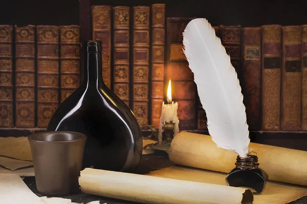 A bottle of wine with a mug, a roll of parchment, a candle on th