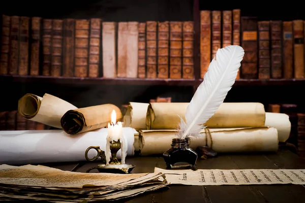 Una vela encendida sobre el fondo de pergaminos borrosos, libros y — Foto de Stock