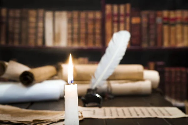 Zapalona świeca na tle niewyraźne zwoje, książek — Zdjęcie stockowe
