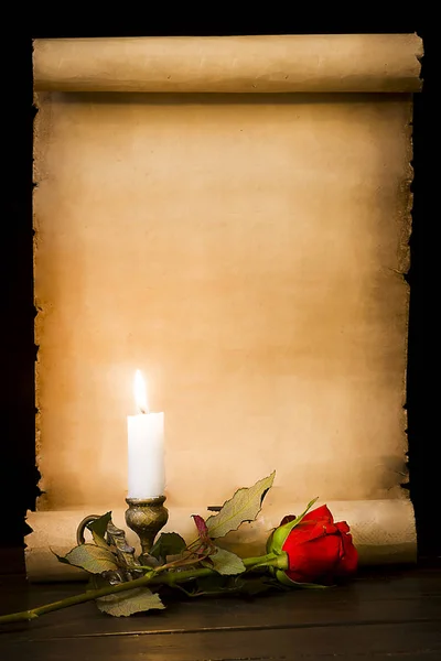 羊皮紙の巻物、赤いバラと火のろうそく — ストック写真