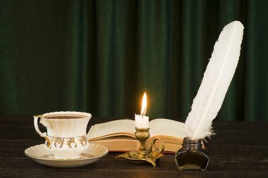 Bir bardak içki, bir tomar papirüs, bir tüy ve bir mum. 