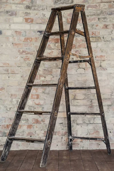 wooden ladder on a brick wall background. Old stepladder