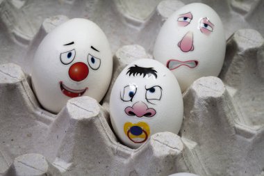 Yumurta tutucuya boyanmış komik yüzlü yumurtalar. Paskalya için yaratıcı yumurta dekorasyon