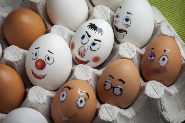 Eggs with funny faces painted in an egg holder. Creative egg decorating for Easter