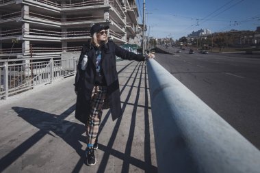 Havalı bir yağmurluk ve şapka giyen güzel, şık bir hanımın açık hava portresi. Model başka yere bakıyor. Şehir yaşam tarzı. Sokak modası konsepti