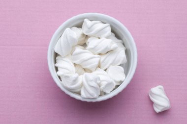 Pembe arka planda beyaz bir porselen tabakta beyaz şekerlemeler. Yukarıdan görüntüle