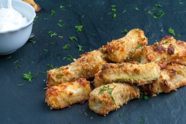 Siyah arka planda parmesan peyniri ve otlarla pişirilmiş kabak. Çubuk şeklinde iştah açıcı kabak. Vejetaryen mutfağı. Sebze tabağı.