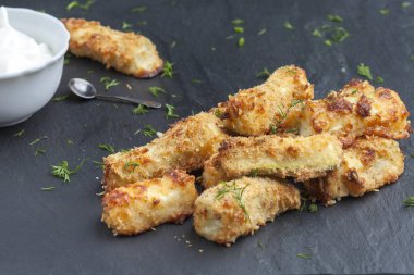 Siyah arka planda parmesan peyniri ve otlarla pişirilmiş kabak. Çubuk şeklinde iştah açıcı kabak. Vejetaryen mutfağı. Sebze tabağı.