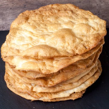 Pişmiş kahverengi yuvarlak kekler gri bir masanın üzerindeki tabakta düzgünce uzanıyorlar. Kremasız kek. Pastanın adı Napolyon..