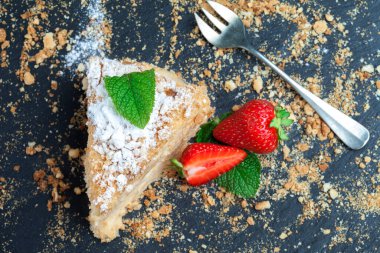 Siyah arka planda, çilek ve nane arkaplanlı, koyu arkaplanda bir parça kek Napolyon. Yukarıdan görünüm