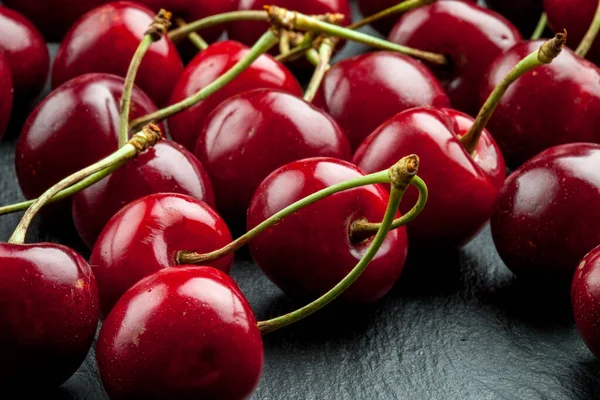 a bunch of ripe sweet cherries with stems and leaves. A large collection of fresh red cherries.