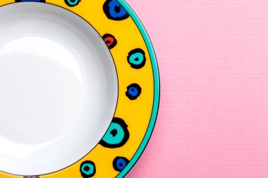 Pembe arka planda izole edilmiş yuvarlak sarı bir tabak.