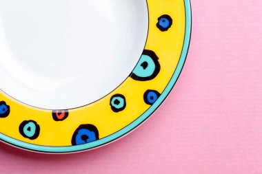 Pembe pastel arka planda parlak çocukların boş tabağı. Tabak çerçevenin sol tarafında. Yukarıdan bak. Çerçevenin sağ tarafındaki metin için boşluk.