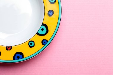 Pembe pastel arka planda parlak çocukların boş tabağı. Tabak çerçevenin sol tarafında. Yukarıdan bak. Çerçevenin sağ tarafındaki metin için boşluk.