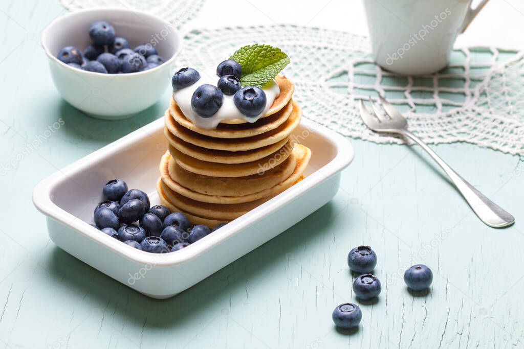 Healthy summer breakfast, homemade classic American pancakes with fresh berries and honey, morning fresh blue background