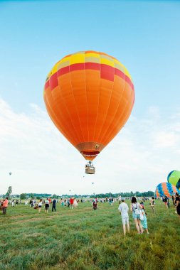 KIEV, UKRAINE - 6 Temmuz 2020: Güneşli mavi gökyüzünde uçan balonların parlak renkli balonlarının görüntüsü. Balon Festivali dikey bir fotoğraf. İnsanlar balon sepetlerinde oturuyorlar..
