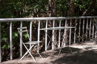 Kahve dükkanında. Boş sonbahar parkında beyaz masa ve sandalye.