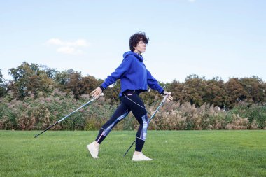 Kiev, Ukrayna - 10 Eylül 2020: Kuzeyde yürüyüş - güzel bir şehir parkında egzersiz yapan orta yaşlı kadın