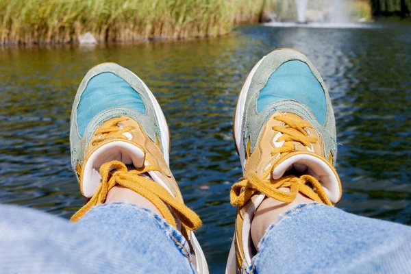 Beine Leuchtend Gelb Blauen Turnschuhen Vor Dem Hintergrund Von Wasser — Stockfoto