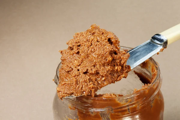 peanut butter in an open close-up on a beige paper background craft paper
