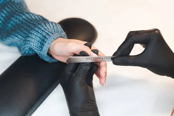 Hands of qualified manicurist filing the nails of woman client — ストック写真