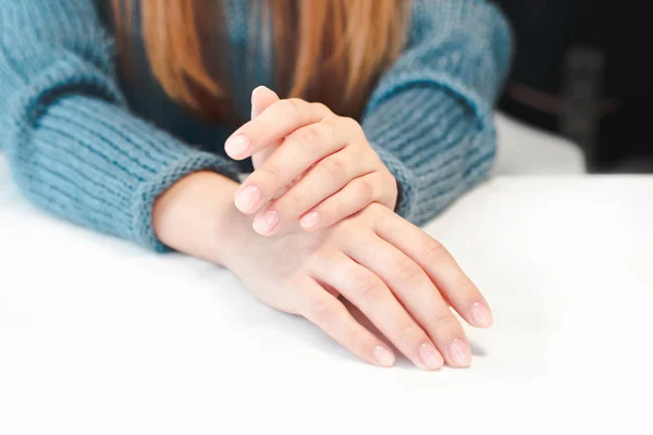 Руки женщины с чистым маникюром и на белом столе крупным планом — стоковое фото