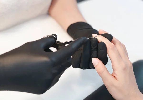 Manos de manicura usando tijeras de uñas cosméticas de metal para cortar cutículas —  Fotos de Stock