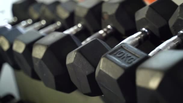 Close-up van rijen van zwarte dumbbells in een sportschool. — Stockvideo