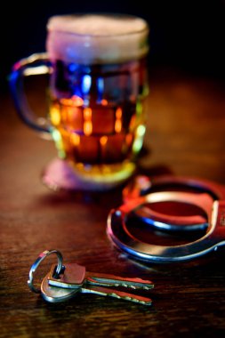Mug of frothy beer with handcuffs and keys symbolizing drunk driving arrest clipart