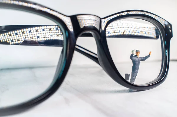 Γυαλιά Οράσεως Που Καθαρίζονται Από Μικροσκοπικό Ειδώλιο Που Συμβολίζει Την — Φωτογραφία Αρχείου
