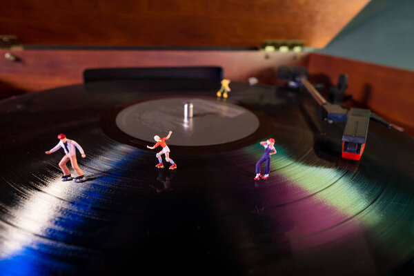 Miniature roller skating figures on vintage vinyl record in macro closeup