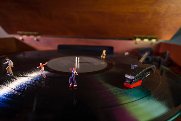 Miniature roller skating figures on vintage vinyl record in macro closeup
