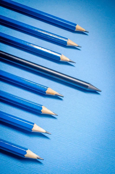 Rows of artist graphite pencils on blue background