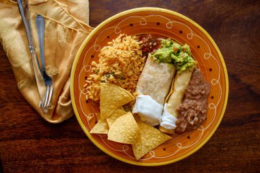 Authentic Mexican burrito and taquito dinner with rice and refried pinto beans clipart