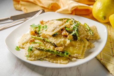 İtalyan peynirli ravioli fırında kavrulmuş kuşkonmaz üzerine limon yağı sosu, üstüne de parmesan peyniri ve karabiber.