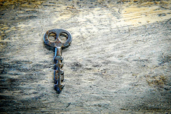 Old antique skeleton key on distressed textured wooden background