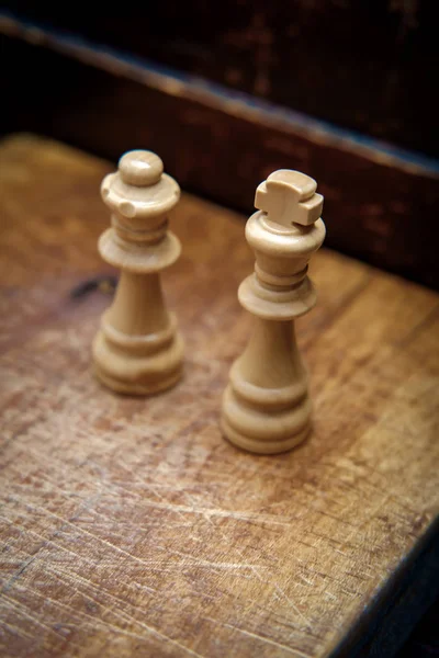 King and Queen chess pieces on rustic worn wooden surface