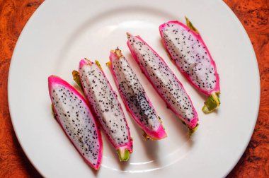 Sulu egzotik pembe ve beyaz dragonfruit tabağa dilimlenmiş.